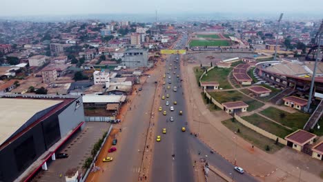 Aerial,-traffic-driving-on-street-next-to-Ahmadou-Ahidjo-Stadium-in-Yaoundé,-Cameroon