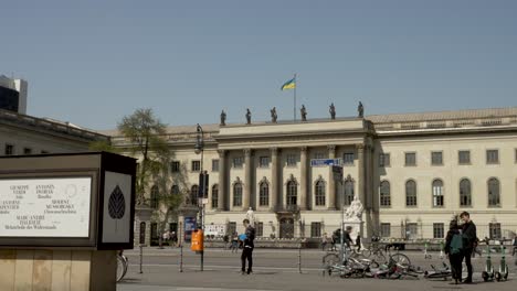 El-Tráfico-Y-La-Gente-Pasando-Por-La-Universidad-Humboldt-De-Berlín-En-Un-Día-Soleado-Con-Cielos-Azules-Y-La-Bandera-De-Ucrania-Ondeando-En-La-Parte-Superior.