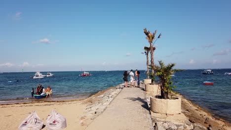 Toma-Manual-De-La-Costa-De-La-Playa-De-Sanur-En-Bali,-Indonesia,-Con-Turistas-Y-Barcos-De-Pescadores-Durante-El-Claro-Horizonte-De-Verano,-Luz-Del-Día.