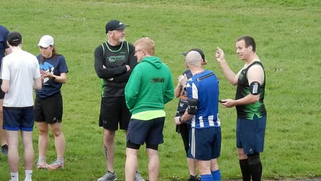 Un-Grupo-De-Corredores-Se-Reunió-Hablando-Y-Apoyándose-Mutuamente-En-El-Campo-Del-Parque-Local-Al-Inicio-De-Su-Carrera-De-Fitness.