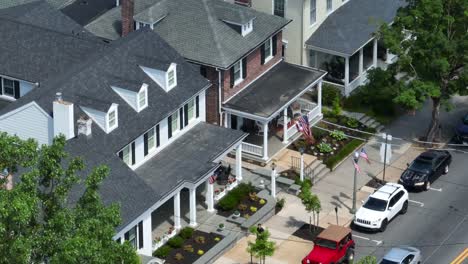 Long-aerial-zoom-of-town-houses-with-street-parking-and-American-flags