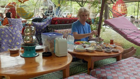 Woman-tourist-eats-Turkish-breakfast-at-colourful-riverside-restaurant-Saklikent