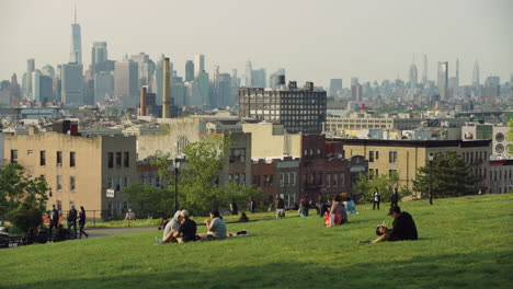 Menschen-Sitzen-Im-Brooklyn-Park-Mit-Dramatischem-Blick-Auf-Die-Innenstadt-Von-Manhattan-In-Der-Ferne