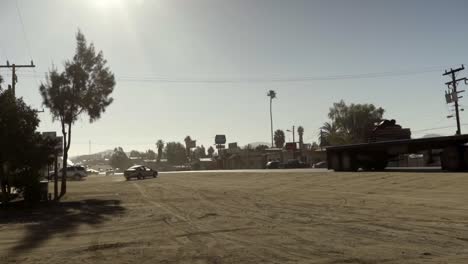 Cámara-Lenta-De-Un-Camión-Grande-Pasa-Por-Un-Camino-Polvoriento-A-Través-De-Un-Pequeño-Pueblo-En-Baja-California