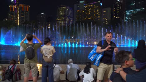 Langsamer-Schwenk-über-Touristen,-Die-Sich-Bei-Der-Berühmten-Wasser--Und-Lichtshow-In-Kuala-Lumpur-Versammelt-Haben