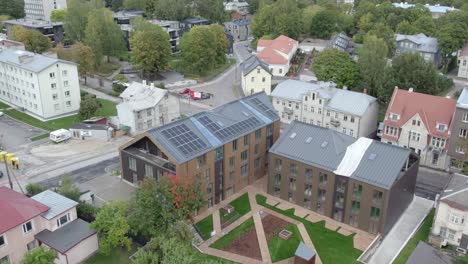 Drone-flying-over-new-apartment-building-Karlovakodu,-Lootuse-2,-there-is-also-Tartu-public-transportation-red-city-bus-driving-by