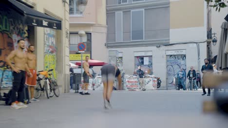 Street-performers-performing-spectacular-athletic-tricks-during-live-street-show-in-front-of-crowd-of-tourists-sitting-at-bars-and-restaurants-in-Barcelona,-Spain-during-sunset-on-warm-evening