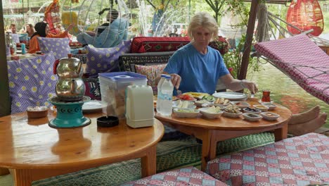 Una-Mujer-Come-Un-Desayuno-Turco-En-Un-Restaurante-Junto-Al-Río-Con-Un-Ambiente-Relajante