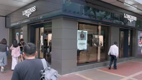 Los-Peatones-Pasan-Por-La-Marca-Suiza-De-Relojes-De-Lujo,-La-Tienda-Longines.