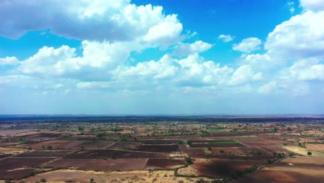 Beautiful-landscape-aerial-camera-down-view-of-agricultural-farm-filled-with-dramatic-clouds-and-empty-farm-in-India