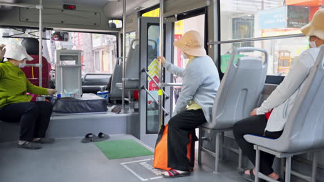 Bus-driver-pickup-people-at-bus-stop,-inside-city-bus-with-people-sitting-on-chairs,-bus-interior