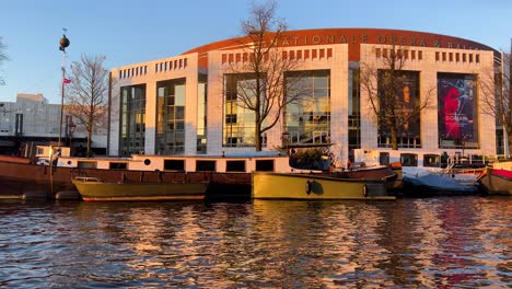 Blick-Durch-Das-Fenster-Eines-Gleitbootes-Auf-Das-Niederländische-Nationaltheater-Für-Oper-Und-Ballett-Bei-Sonnenuntergang