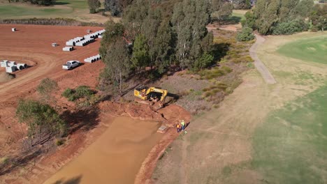 Yarrawonga,-Victoria,-Australia---2-June-2023:-Two-workmen-watching-a-tracked-excavator-digging-dirt-in-a-new-billabong-at-a-golf-course-in-Yarrawonga-Victora