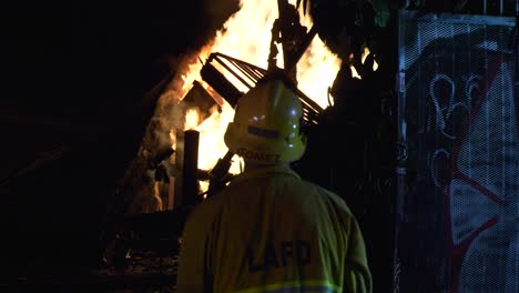 LAPD-Firefighter-watching-a-house-on-fire,-late-night-in-Los-Angeles,-USA