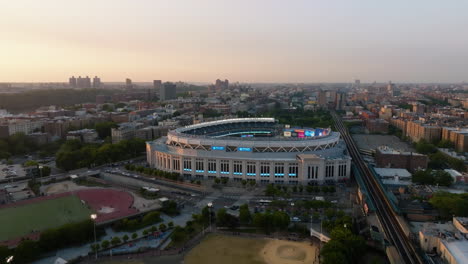 Vista-Aérea-Hacia-Atrás-Lejos-Del-Estadio-Yankee,-Puesta-De-Sol-En-El-Bronx,-Nueva-York