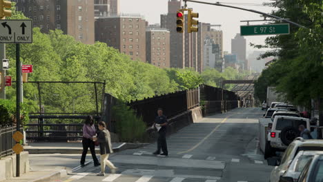 Fußgänger-überqueren-Die-Straße-Von-Manhattan,-New-York,-Unter-Der-Ein-Pendlerzug-Vorbeifährt