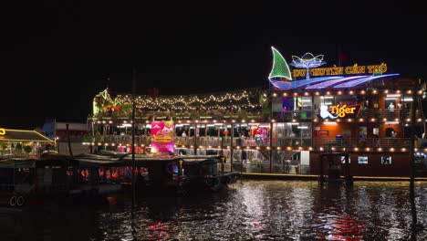 A-colorful-floating-restaurant-ship-in-Can-Tho-city,-illuminated-by-colorful-LED-lights-on-the-river-harbor-at-night
