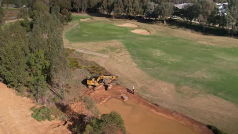 Yarrawonga,-Victoria,-Australia---2-June-2023:-Circling-around-a-tracked-excavator-and-two-workmen-working-on-a-golf-course-in-Yarrawonga-Victoria