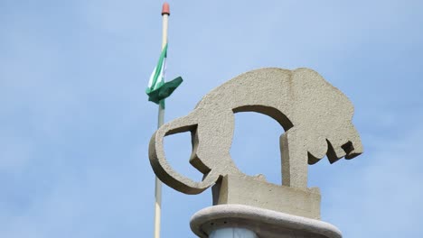 Steinschnitzerei-Im-Rotterdamer-Zoo-Mit-Der-Flagge-Von-Rotterdam,-Die-Im-Wind-Vor-Dem-Klaren-Blauen-Himmel-Im-Hintergrund-Flattert