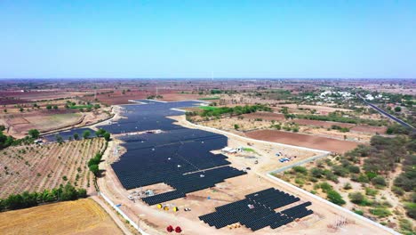 Eine-Luftdrohnenkamera-Bewegt-Sich-Vorwärts-Und-Zeigt-Einen-Gesamten-Solarpark,-Der-Grüne-Energie-Produziert-Und-An-Ein-Nahegelegenes-Kraftwerk-Liefert