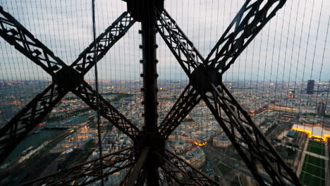 Elevator-going-up-the-floors-of-the-Eiffel-Tower-overlooking-the-city-of-Paris-city-at-dusk