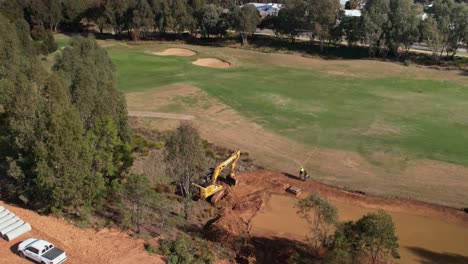 Yarrawonga,-Victoria,-Australia---2-June-2023:-Tracked-excavator-moving-along-beside-a-new-fairway-billabong-on-a-golf-course-in-Yarrawonga-Victoria