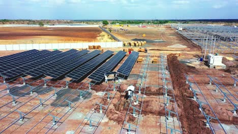 3153-Arbeiter-Holen-Die-Solarpaneele-Und-Module-Ab,-Die-Im-Solarkraftwerk-In-Indien-Montiert-Werden-Sollen,-Eine-Luftdrohnenkamera-Folgt