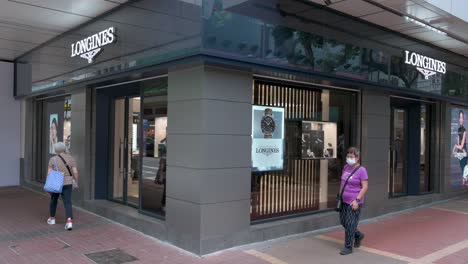 Chinese-pedestrians-walk-past-the-Swiss-luxury-watchmaker-brand,-Longines-store