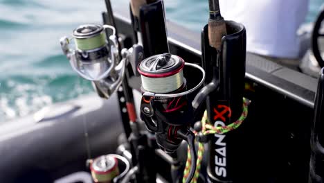 Fishing-rods-securely-placed-in-the-boat-holding-area-with-captain-steering-behind,-Close-up-shot