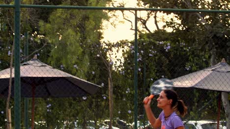 Woman-hitting-a-forehand-in-slow-motion-playing-beach-tennis-at-sunset