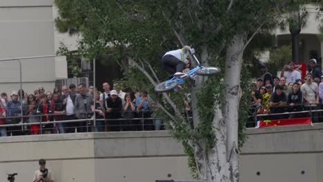 Ein-BMX-Champion-Macht-Einen-Trick-Mit-Seinem-Blauen-BMX,-In-Zeitlupe,-Beim-Berühmten-Fise-In-Montpellier,-Frankreich,-Mit-Zuschauern-Im-Hintergrund,-Vielen-Menschen-Mit-Kamera,-Die-Ihn-Fotografieren