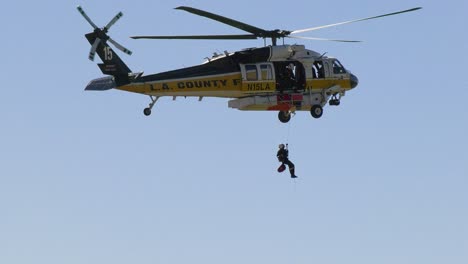 Helicóptero-Del-Condado-De-La-Arrojando-Al-Suelo-A-Un-Combatiente-De-Rescate,-En-La-Soleada-California,-EE.UU.