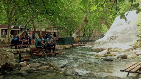 People-shaded-at-Saklikent-gorge-enjoy-drinks-in-rocky-fast-flowing-river