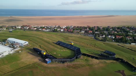 Preparations-for-The-2023-Open-at-Royal-Liverpool-Golf-Club,-Wirral,-UK---Aerial-drone-18th-green-anti-clockwise-pan-from-high-and-far,-course-and-area-reveal