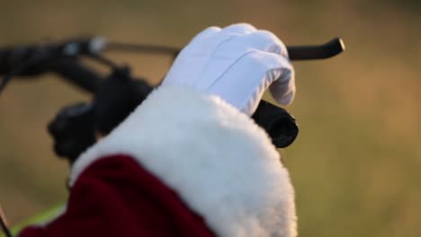 The-hand-and-sleeve-of-the-red-coat-of-santa-claus-on-the-handlebar-of-a-bicycle