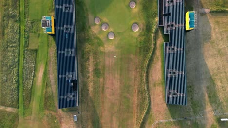 Preparations-for-The-2023-Open-at-Royal-Liverpool-Golf-Club,-Wirral,-UK---Aerial-drone-gimbal-down-view-of-18th-green-with-grand-stand