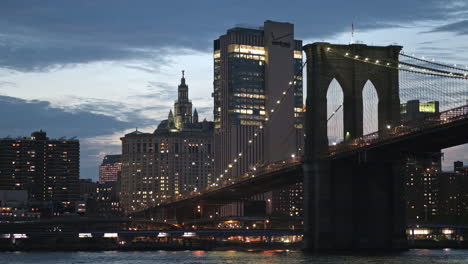 Twilight-view-over-East-River-of-iconic-lit-up-Brooklyn-Bridge-in-New-York,-USA