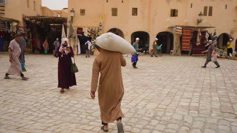 Hombre-Adulto-Llevando-Un-Saco-Al-Hombro-Al-Mercado-De-Ghardaia-En-Argelia