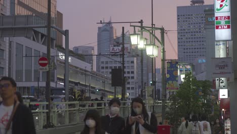 Lugareños-Con-Máscaras-Faciales-Caminando-Afuera-De-La-Estación-Shinjuku-Durante-La-Hora-Dorada,-Luz-En-El-Cielo
