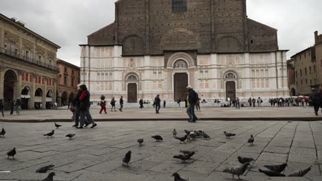 Tourists-walking-on-the-street-of-Basilica-of-San-Petronio-on-Piazza-Maggiore-in-Bologna,-Emilia-Romagna,-Italy