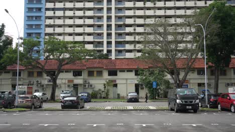 Scene-of-a-man-walking-in-the-open-air-car-park-against-the-background-of-the-Housing-Development-Board-,-a-housing-residential-area-in-Whampoa-Estate,-Singapore