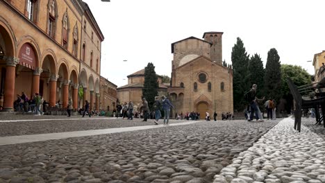 Touristen-Gehen-über-Die-Piazza-Santo-Stefano-Mit-Der-Basilika-Von-Santo-Stefano-Im-Hintergrund-In-Bologna