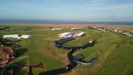 Preparations-for-The-2023-Open-at-Royal-Liverpool-Golf-Club,-Wirral,-UK---Aerial-drone-18th-green-clockwise-pan-from-far,-area-and-course-reveal