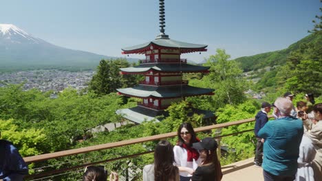 Tourists-At-Chureito-Pagoda-Viewpoint-On-Sunny-Clear-Day-With-Pan-Left-Reveal-Of-Snow-Capped-Mount-Fuji-In-Background