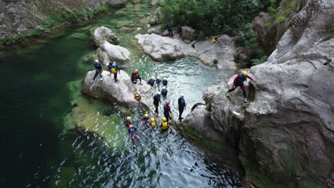 Group-of-people-canyoneering-and-cliff-jumping-in-Cetina-river-water-at-Gubavica-Waterfall,-omis---Croatia