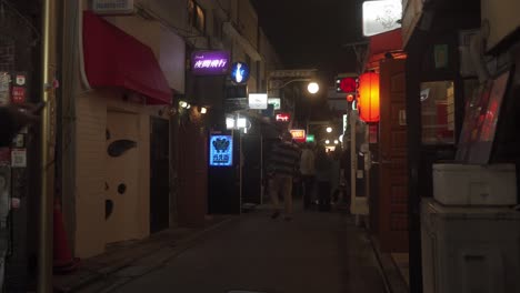 Tokyo-Locals-Walking-Past-Local-Narrow-Street-In-Golden-Gai,-Shinjuku-At-Night