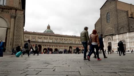 Tourists-walking-on-the-beautiful-street-of-Piazza-Maggiore-Square-with-Italian-monuments-and-gothic-buildings-at-the-background,-Bologna