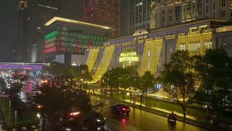 Aerial-view-of-Taipei-city-at-night-with-busy-traffic-on-road-and-xmas-decoration-at-Bellavita-Shopping-Center,-Taiwan