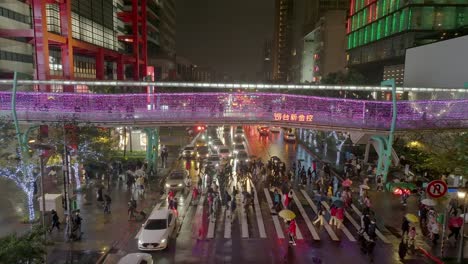 Drone-shot-of-pedestrian-crossing-bridge-and-crosswalk-during-rainy-day-at-night-in-Taipei-City---Chrismas-decorated-Bridge-and-buildings