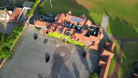 Preparations-for-The-2023-Open-at-Royal-Liverpool-Golf-Club,-Wirral,-UK---Aerial-drone-gimbal-down-and-descend,-clubhouse-front-reveal